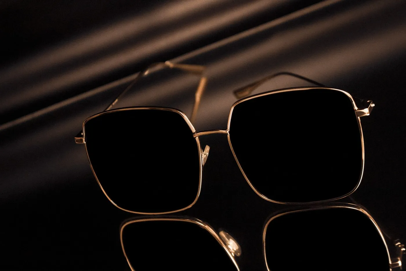 Lunettes de soleil carrées à monture dorée sur fond noir